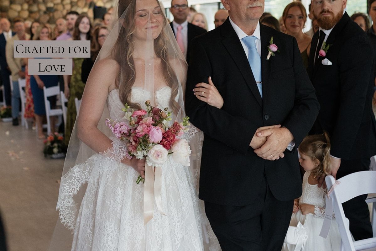 Bride in a long lace veil holding a bouquet while walking down the aisle